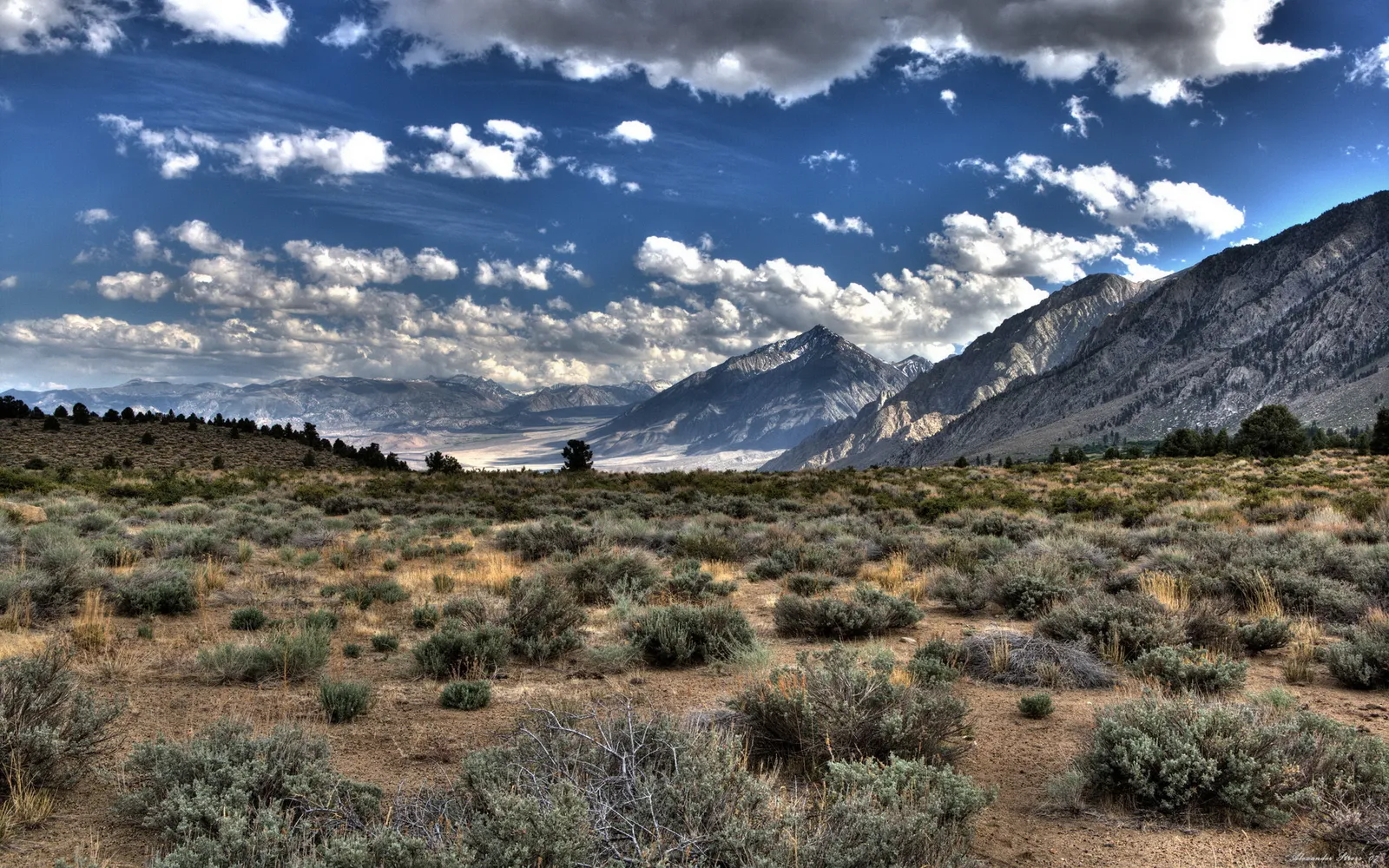 A wide view of rugged mountains under a dramatic sky with scattered clouds.