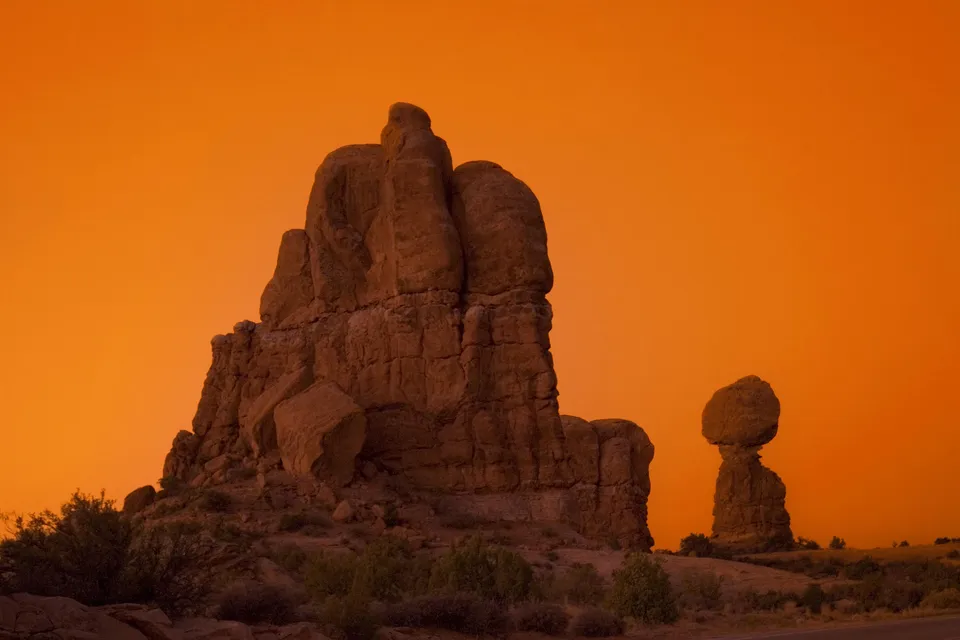 Balanced Rock in Arches National Park during a vibrant orange sunset.