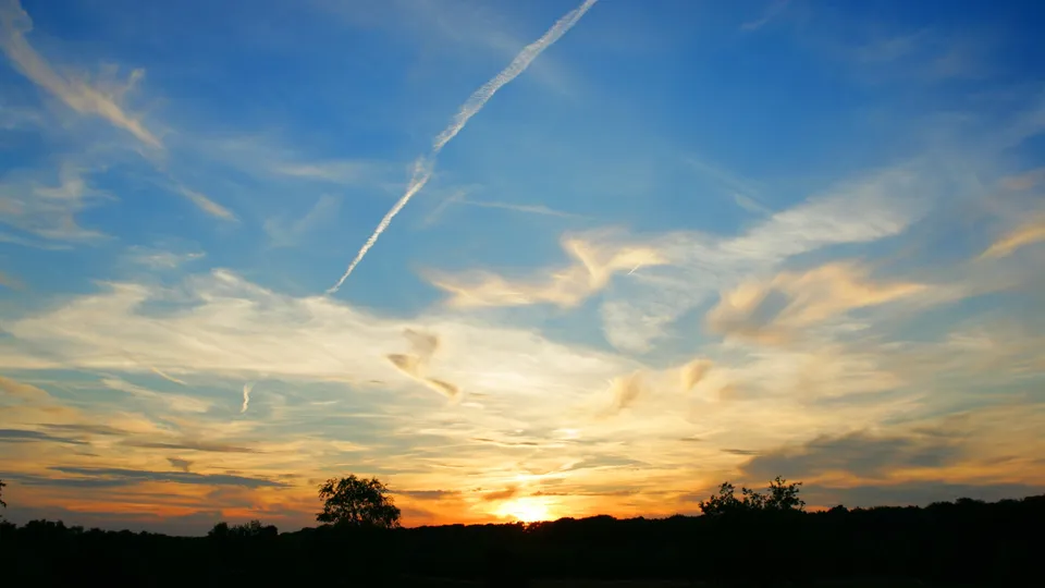 A sunset sky transitions from deep blue to orange with scattered wispy clouds.