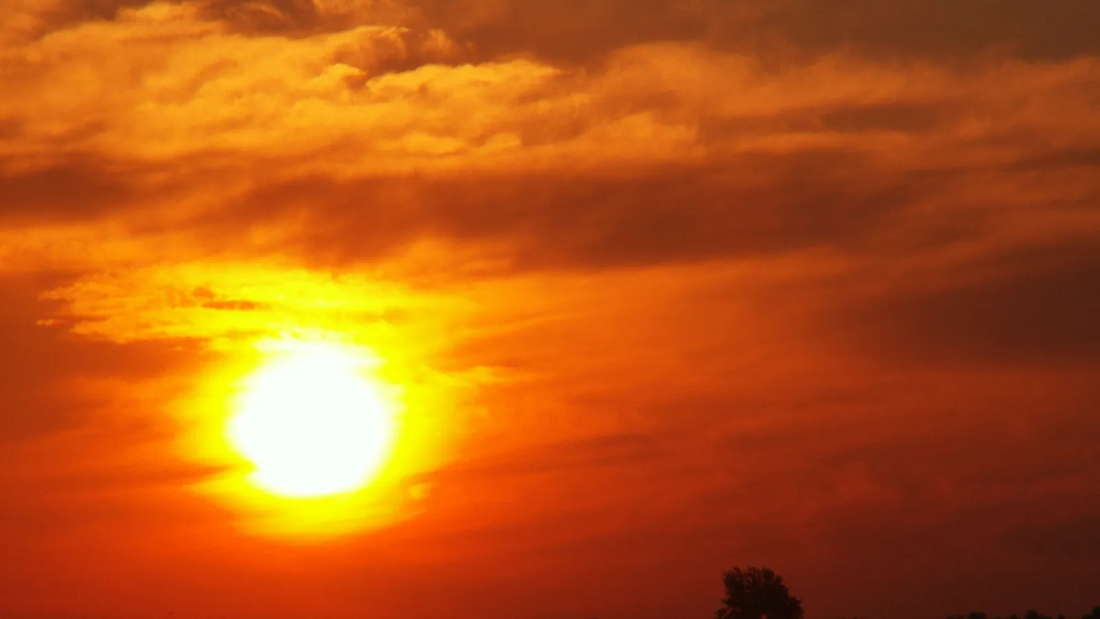 The sun is a brilliant white orb radiating intense yellow and orange light as it descends towards the horizon.