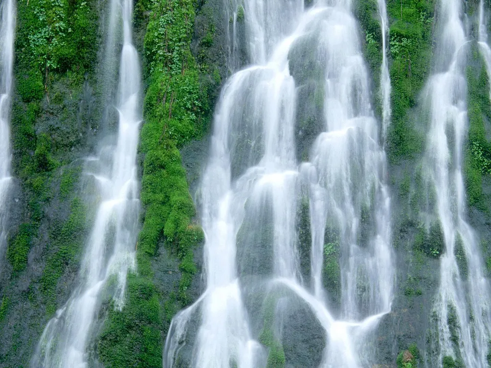 A close-up view of a multi-tiered waterfall with lush green moss covering the rocks.