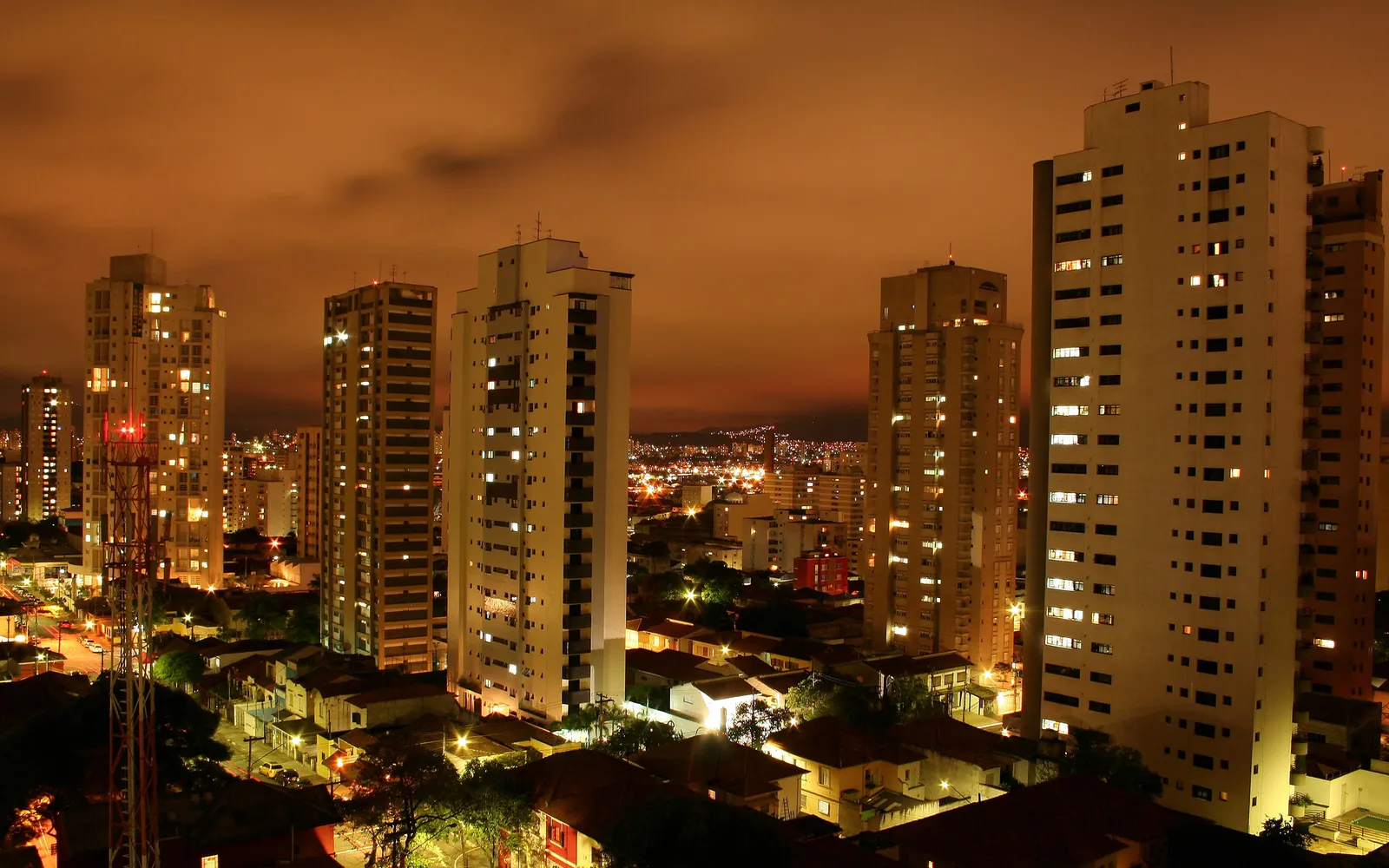 A nighttime view of a city skyline with tall buildings illuminated by interior lights.