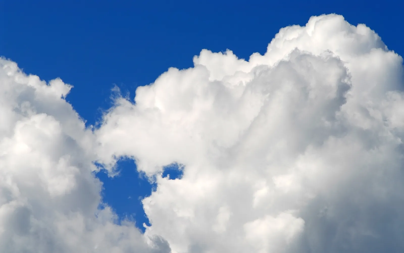 Large, fluffy white cumulus clouds fill the sky, with patches of deep blue visible between them.