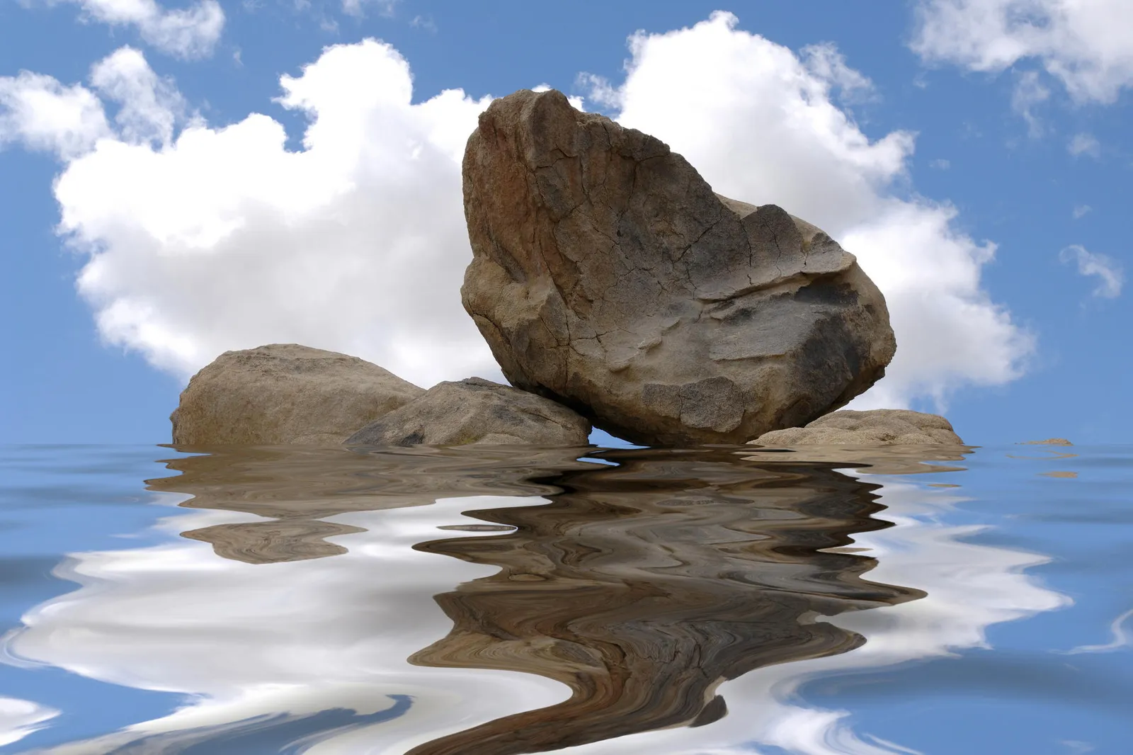 Large boulders are reflected in rippling water under a blue sky with white clouds.