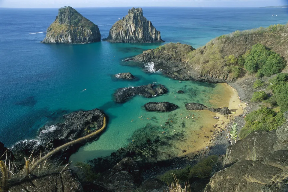 Aerial view of Dois Irmaos Islands and a tropical bay with clear turquoise water and a sandy beach.