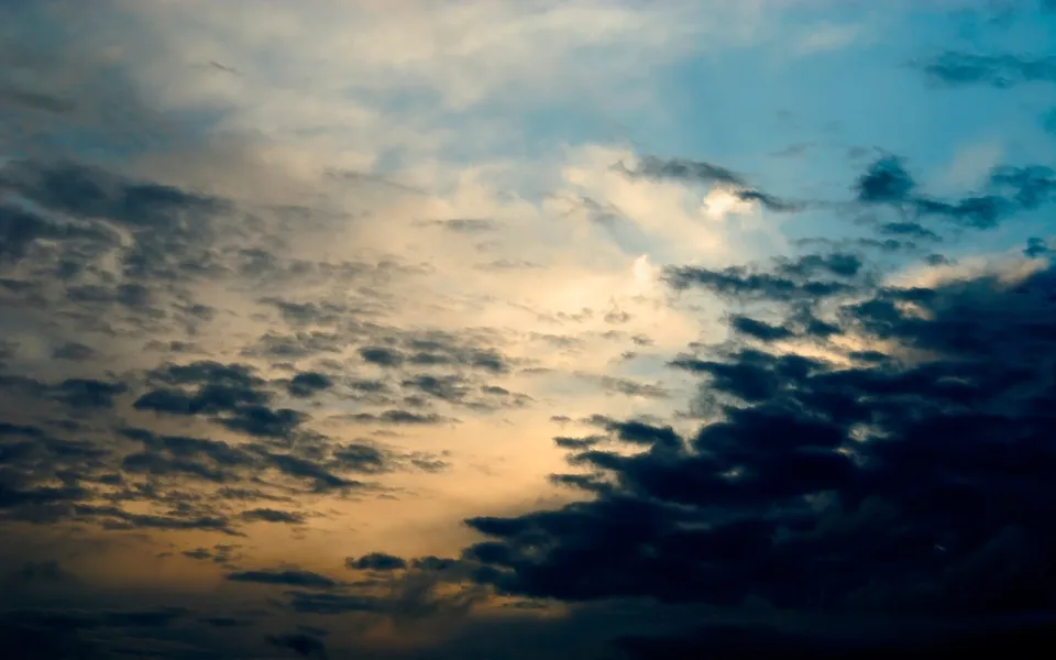 Dark and light clouds are illuminated by the setting sun, creating a dramatic sky.