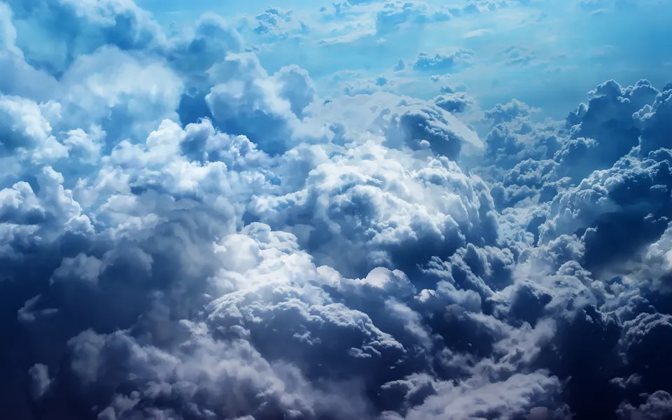 A view from above showing a vast expanse of turbulent cumulonimbus clouds with dramatic lighting.
