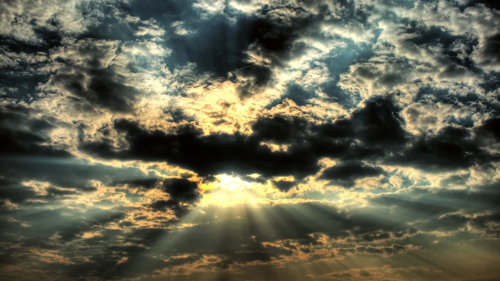 Sunlight streams through dark, dramatic clouds, creating visible sunbeams.