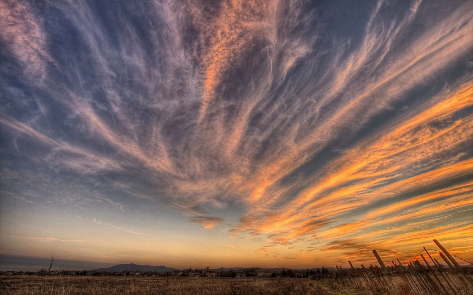A dramatic sky filled with wispy clouds illuminated by the warm colors of sunset.