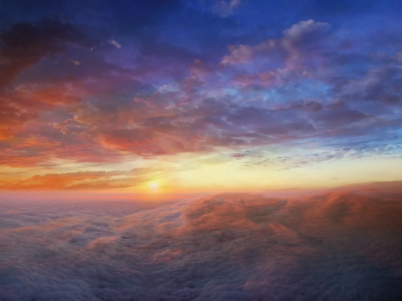 A vibrant sunset paints the sky with fiery oranges and deep blues above a vast sea of clouds.