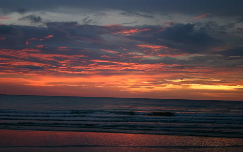 The sky is ablaze with vibrant hues of orange and red, with darker clouds.