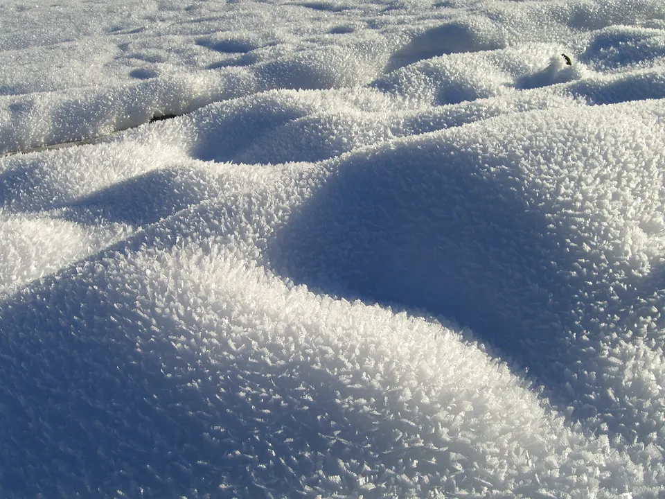 Close-up of snowdrifts covered in delicate ice crystals, casting shadows.