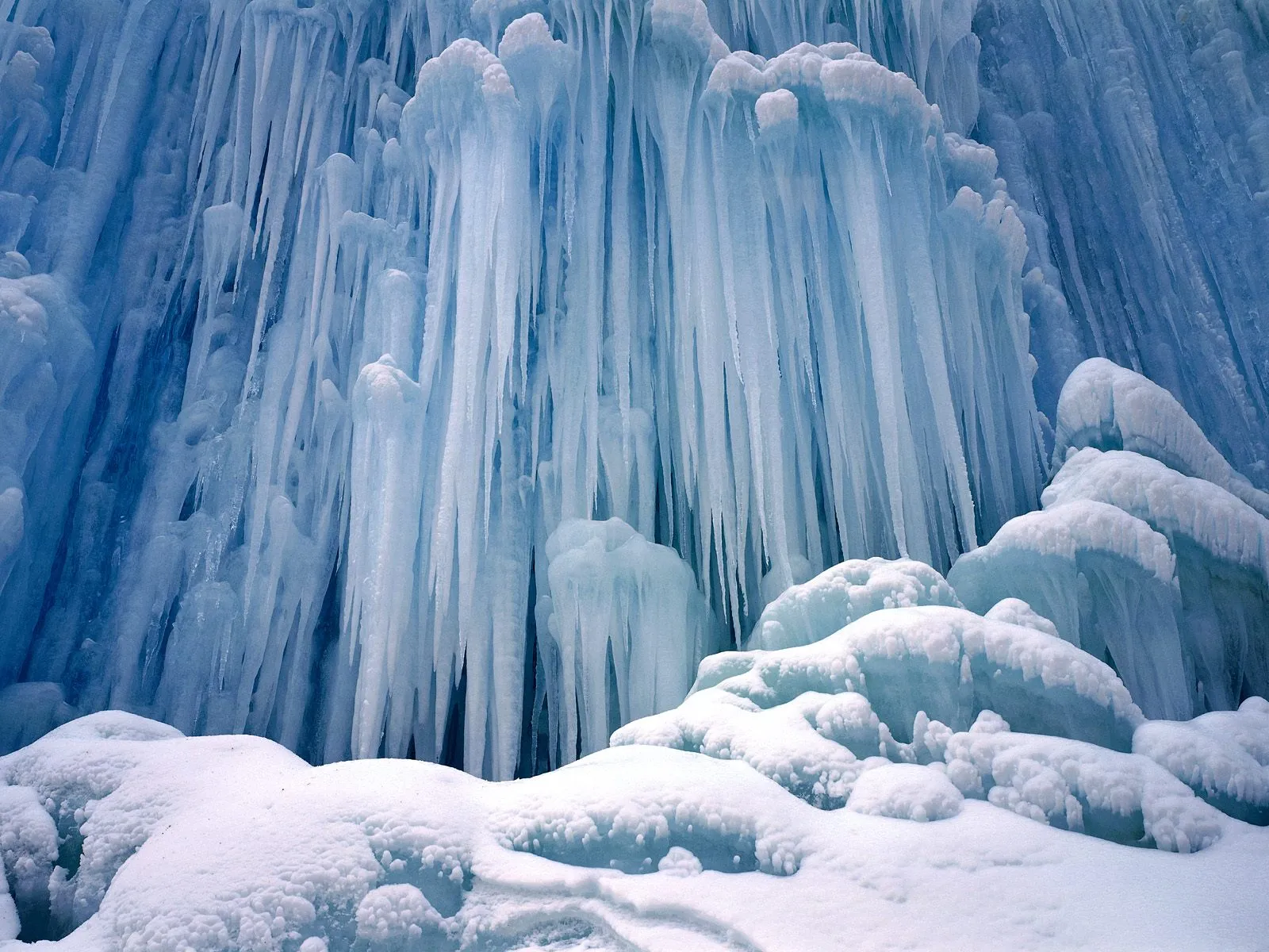 A close-up view of numerous icicles and snow-covered mounds in a winter landscape.