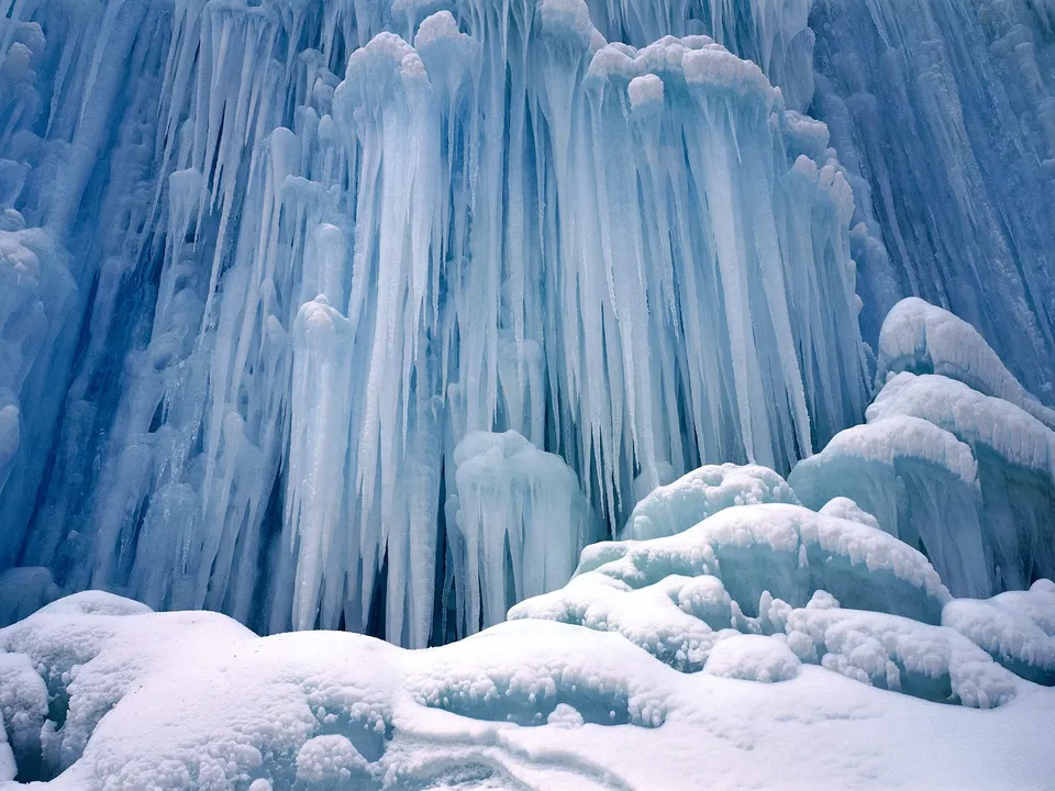 A close-up view of numerous icicles and snow-covered mounds in a winter landscape.