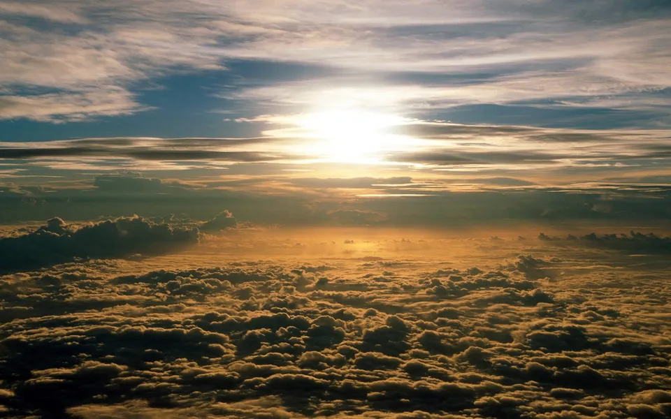 Golden sunlight illuminates a vast sea of clouds during the golden hour.
