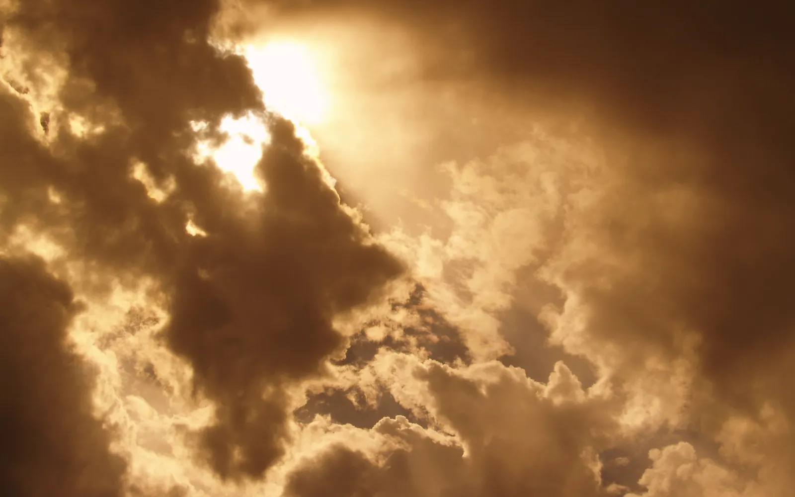 Sunbeams break through dark storm clouds, creating dramatic shafts of light.