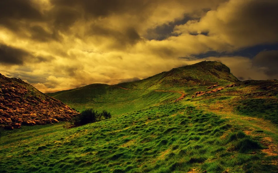 Rolling green hills under a dramatic, golden-yellow cloudy sky.