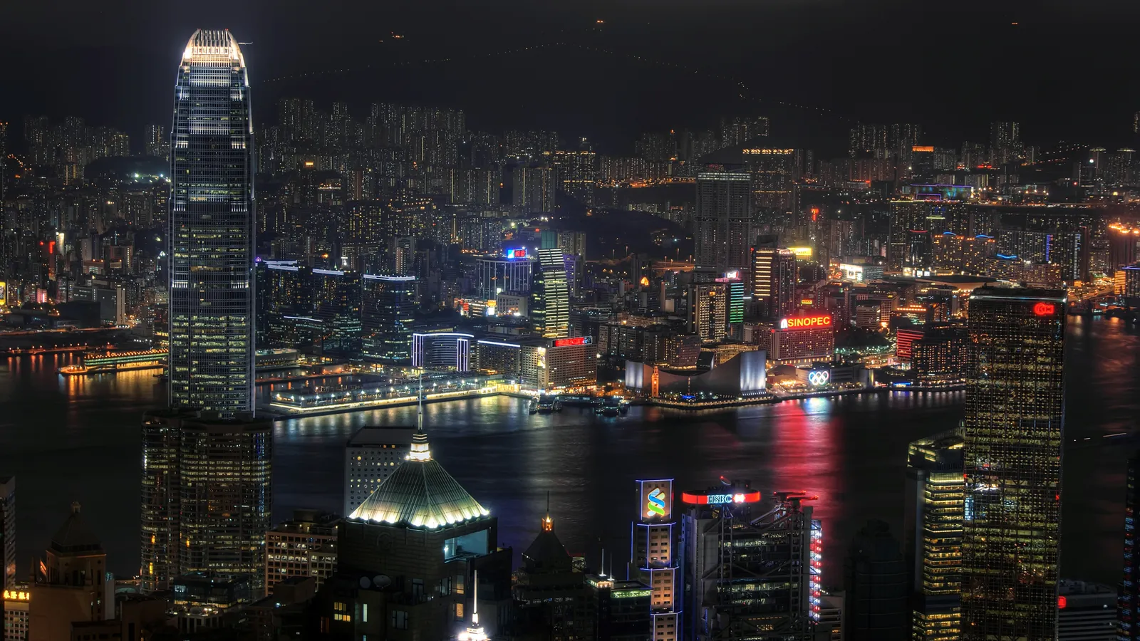 A panoramic view of the illuminated Hong Kong cityscape from a high vantage point at night.