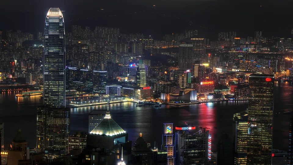 A panoramic view of the illuminated Hong Kong cityscape from a high vantage point at night.