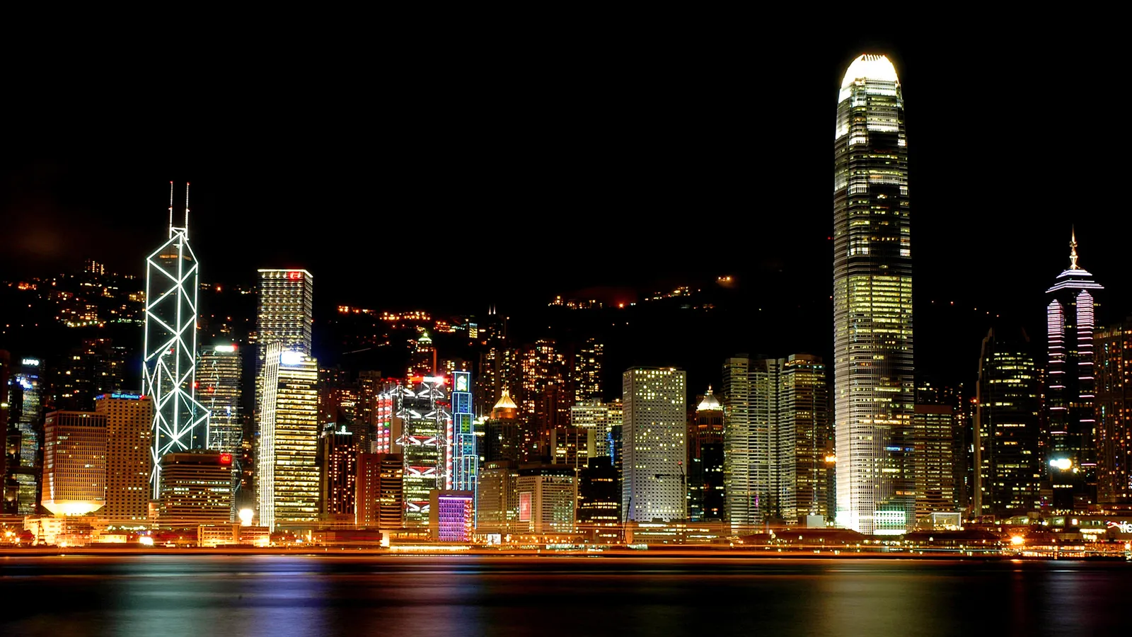 The Hong Kong skyline at night is illuminated with many buildings and the IFC tower prominent.