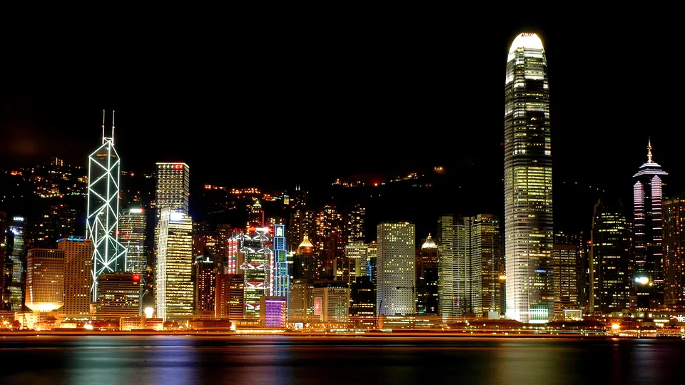 The Hong Kong skyline at night is illuminated with many buildings and the IFC tower prominent.