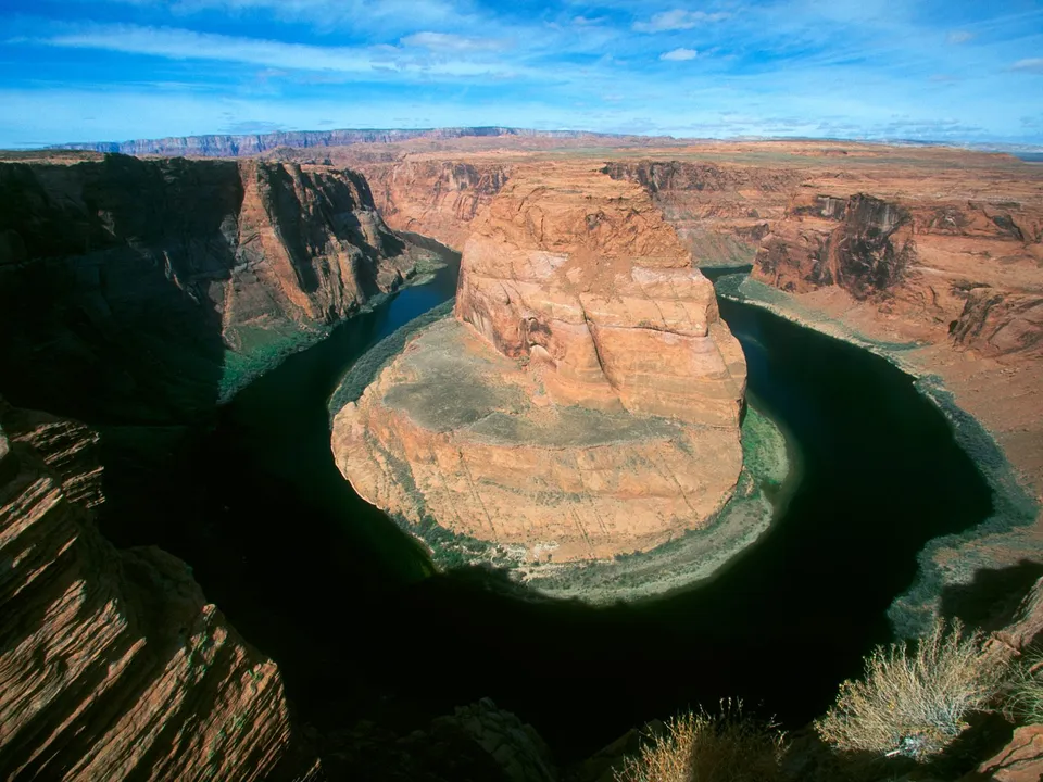 Horseshoe Bend canyon with blue river and bright blue sky.