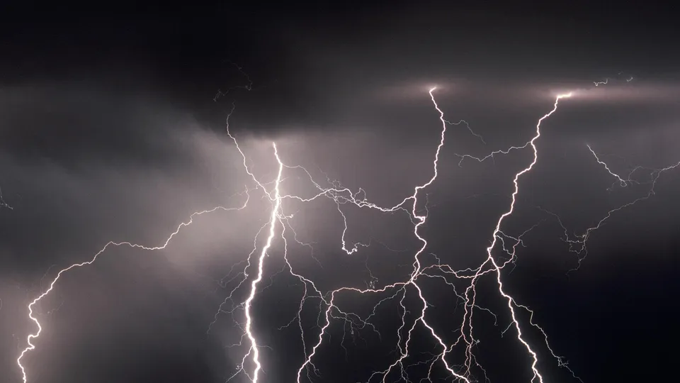Jagged lightning bolts illuminate dark, turbulent storm clouds with bright white light.