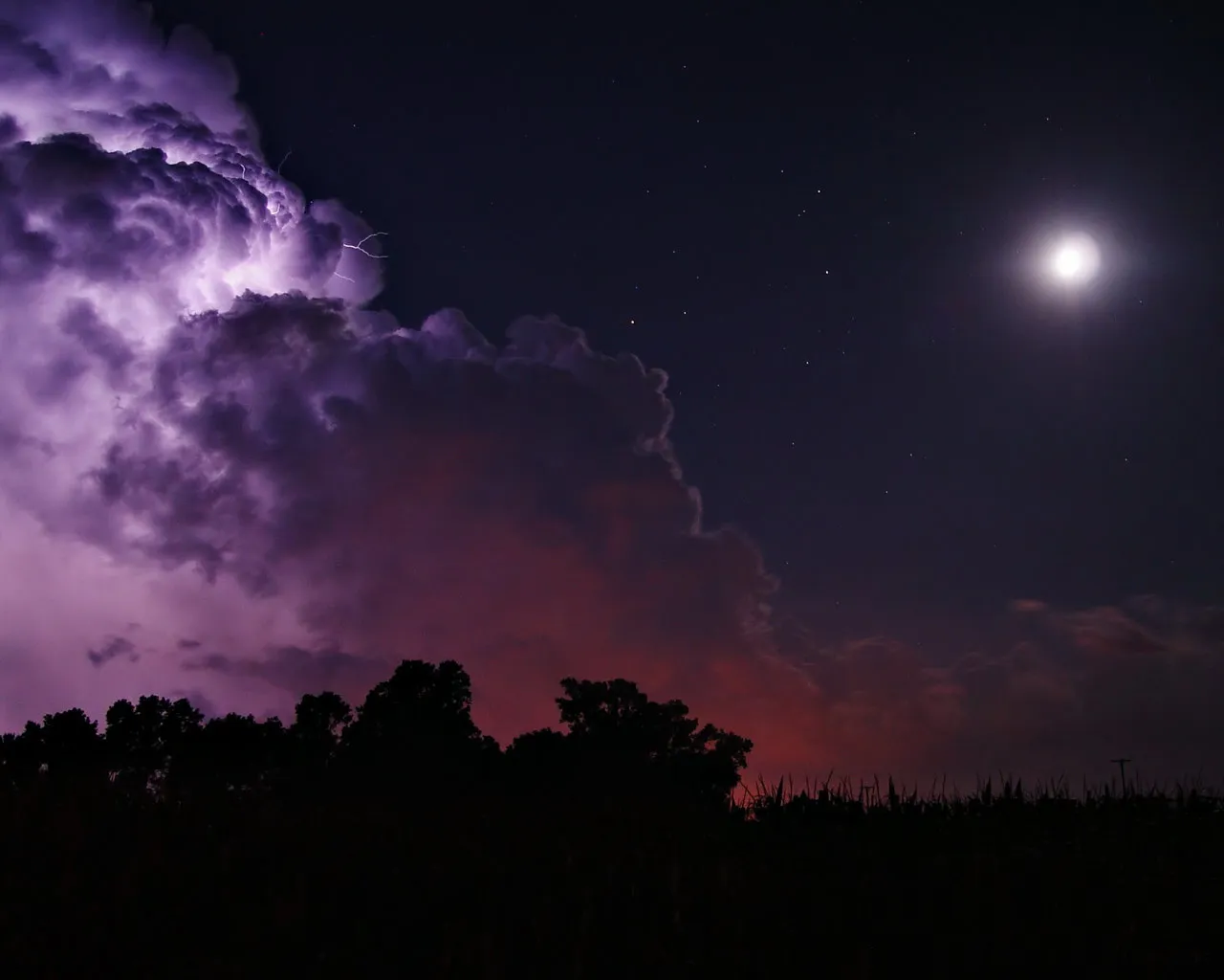 A dramatic lightning storm illuminates dark clouds with purple light, under a starry night sky with a bright moon.