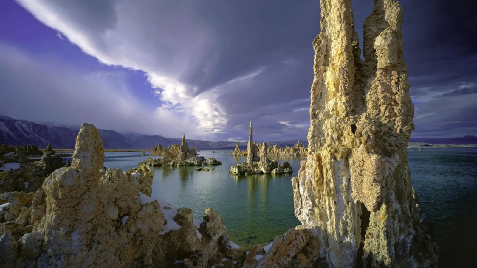 Tufa towers rise from the water of Mono Lake under a dramatic, cloudy sky.