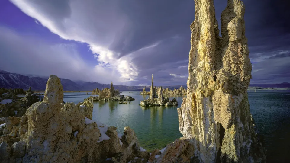 Tufa towers rise from the water of Mono Lake under a dramatic, cloudy sky.