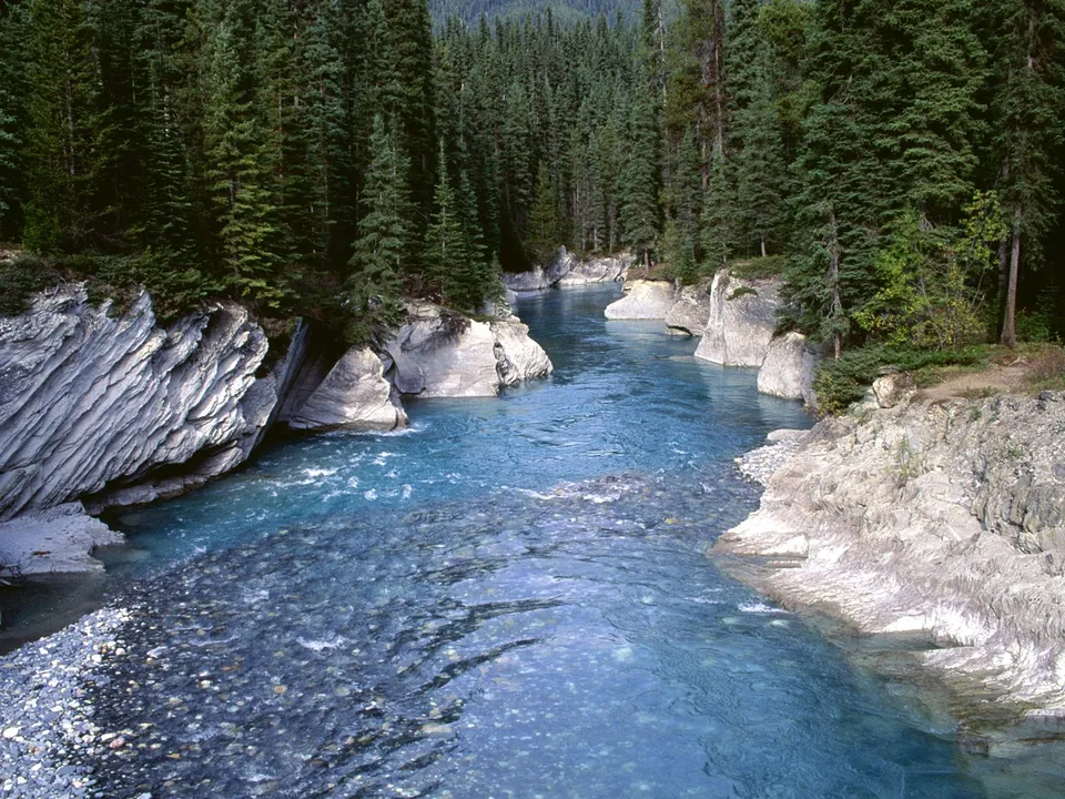 A bright turquoise river flows through a rocky canyon with steep, forested banks.