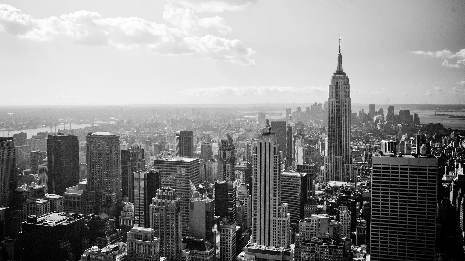 A black and white aerial view of the New York City skyline, featuring the Empire State Building prominently.