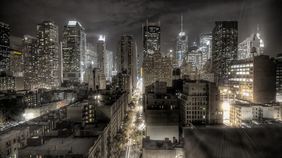 A high-angle view of the New York City skyline at night, with illuminated skyscrapers and city lights.