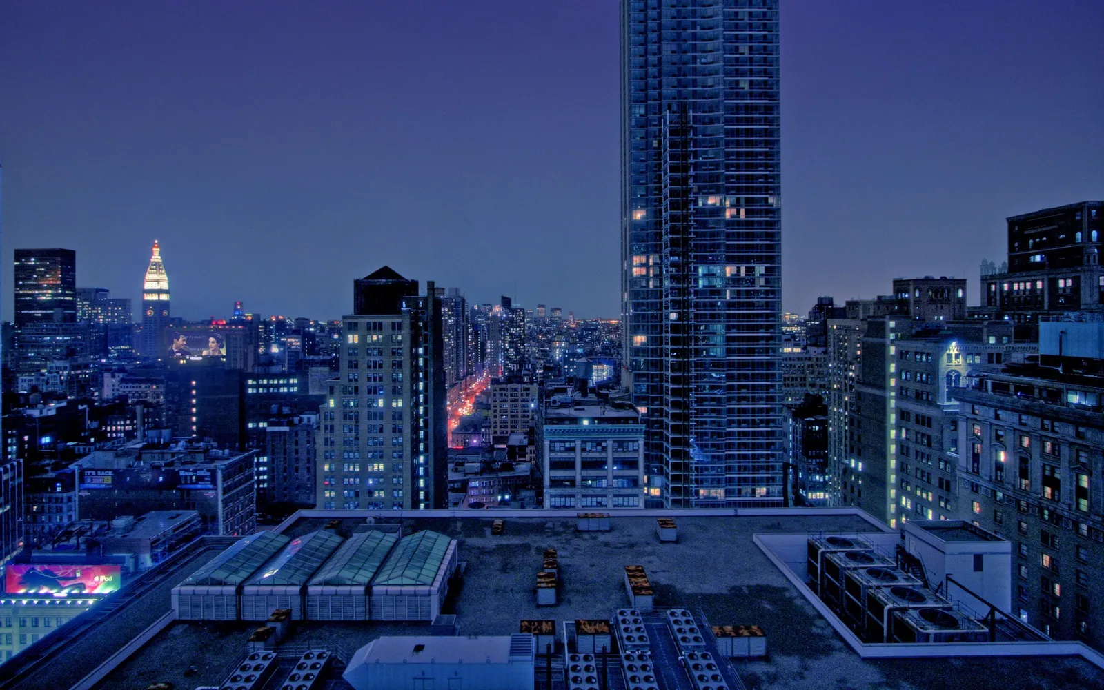 A wide shot of the New York City skyline at dusk, with many buildings lit up.
