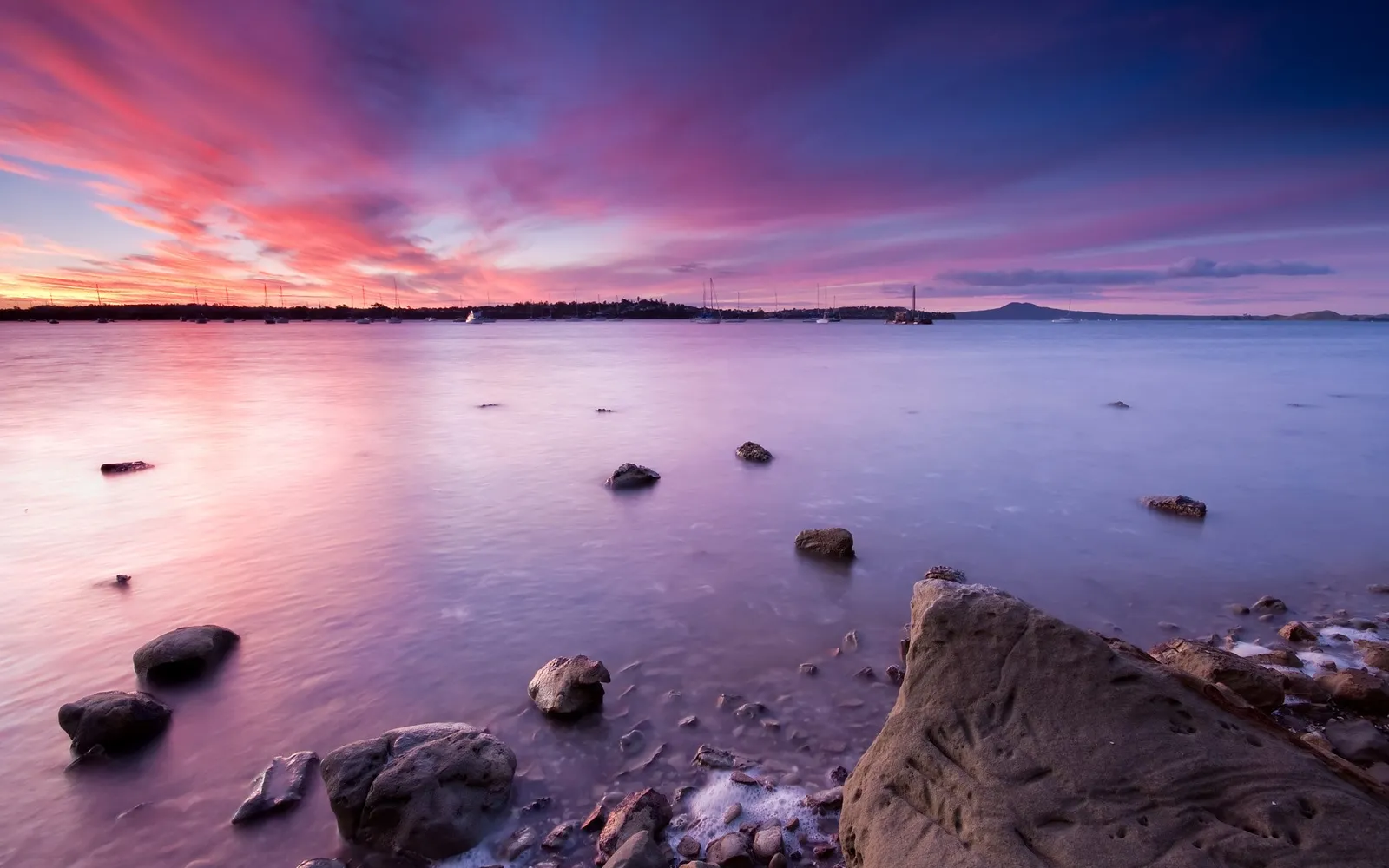 Pink and purple streaks fill the sky during a dramatic sunset over the ocean.