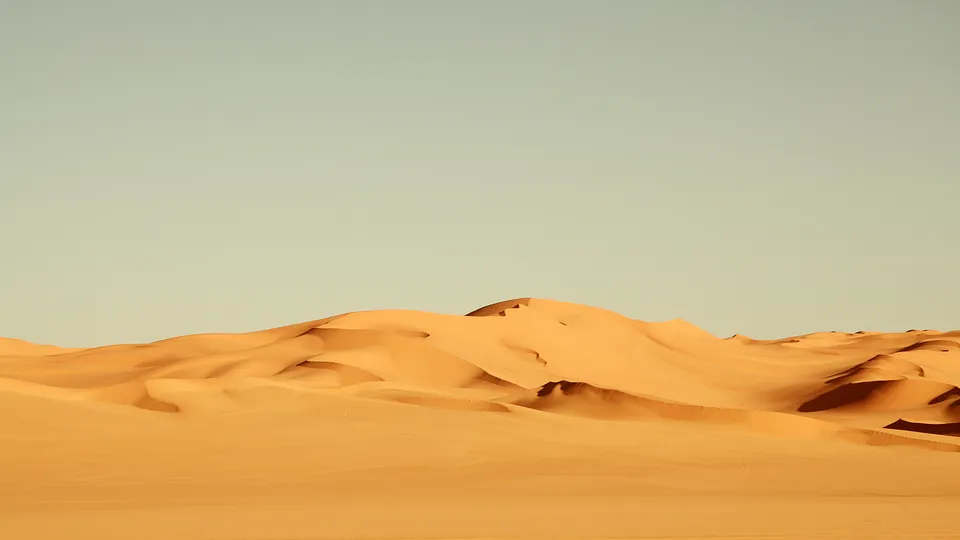 Gentle shadows highlight sand textures on serene desert dunes.
