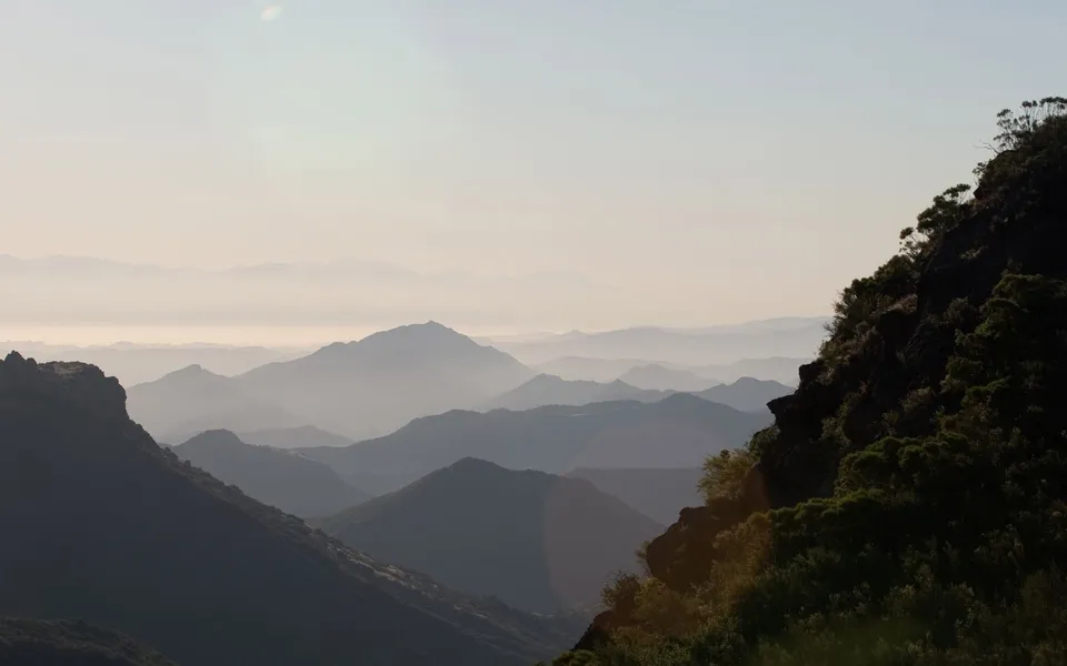 Distant mountain layers are softened by atmospheric haze in the early morning light.