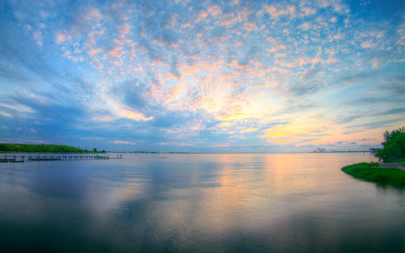 A serene sunset with soft pink, orange, and blue hues in the sky, reflected in the calm water.