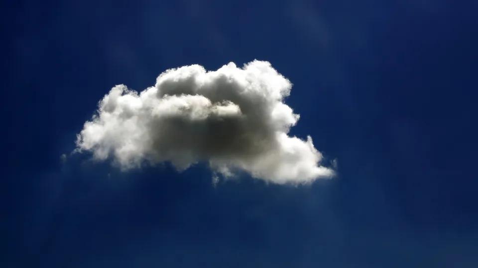 A single, fluffy cumulus cloud floats in a vast, deep blue sky.