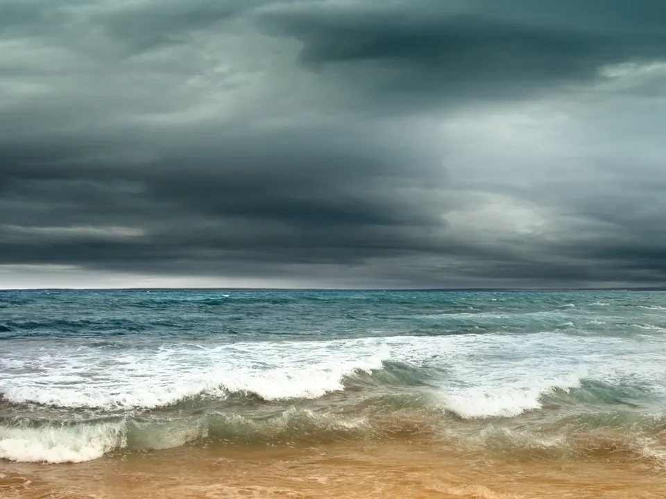 A turbulent sea with white-capped waves under a dark, cloudy sky.