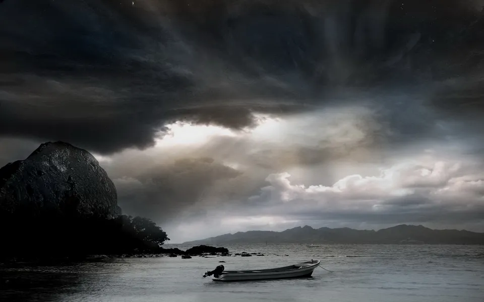 A small boat floats on the water under a dark, dramatic sky with swirling clouds and a bright break.