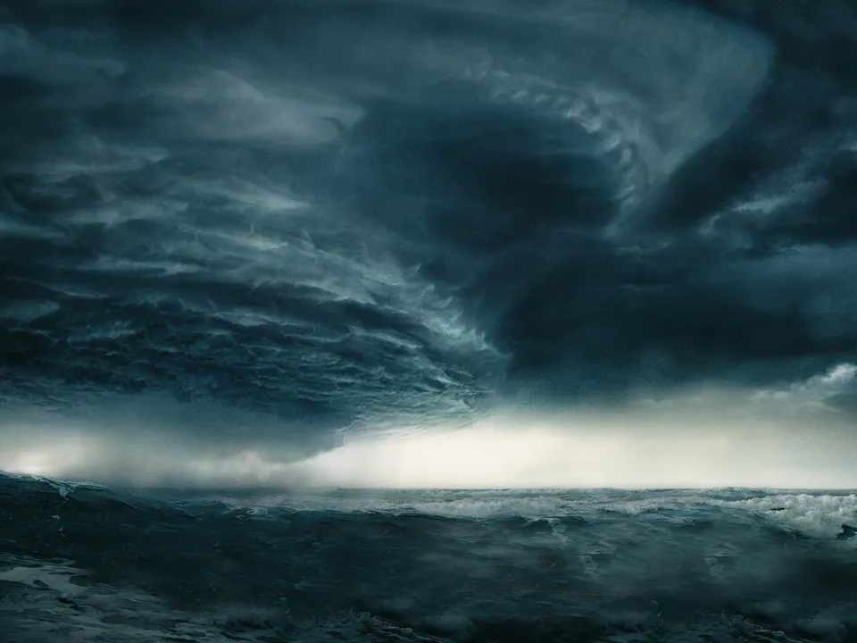 A turbulent ocean with large waves under a dark, dramatic storm cloud formation.