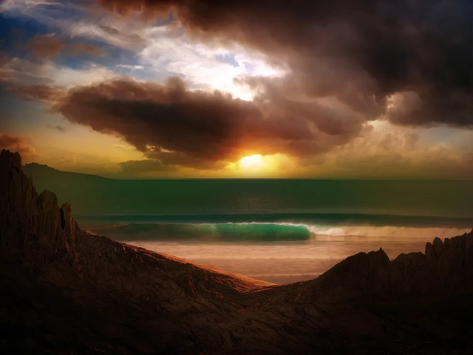 Sunlight breaks through dark clouds onto a turquoise wave and rugged coast.