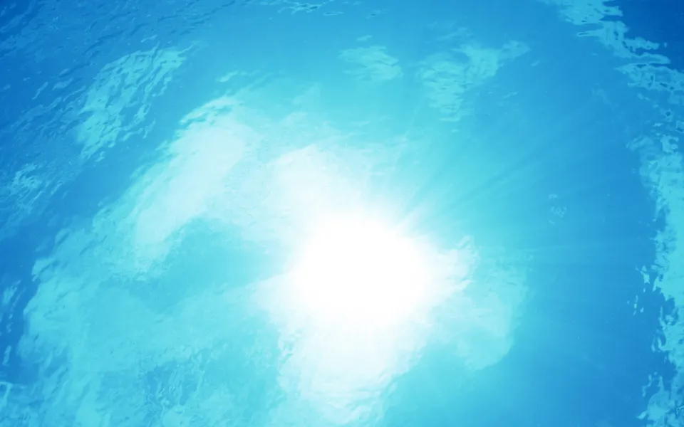Sunlight beams shining through the surface of clear blue ocean water.