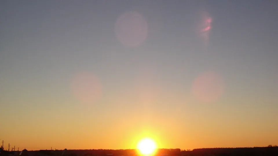 The sun is setting on the horizon, casting a warm golden glow across the sky.