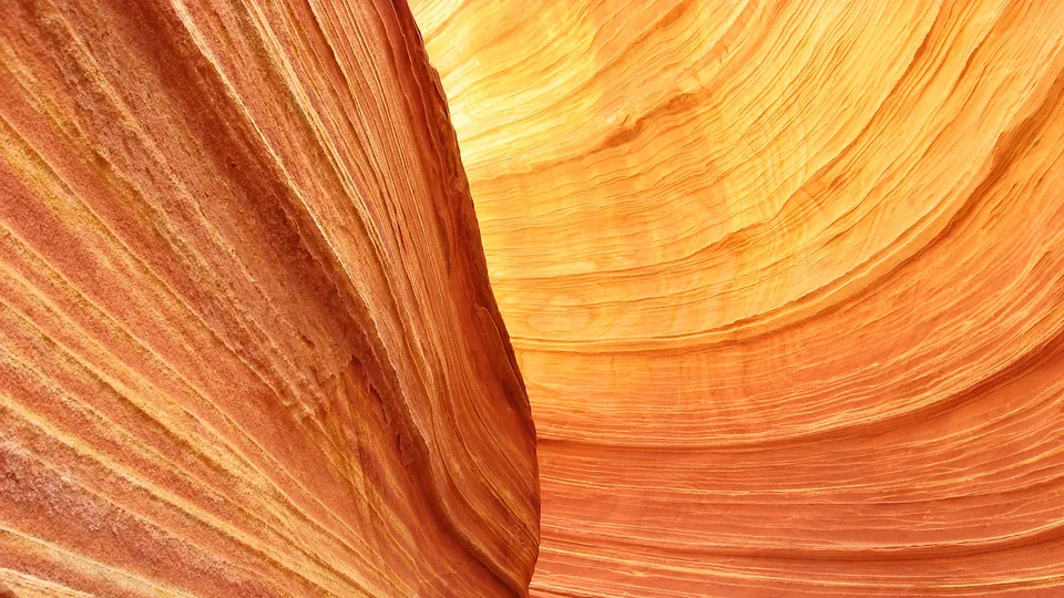 Close-up view of undulating sandstone rock formations with distinct horizontal layers in shades of orange and yellow.