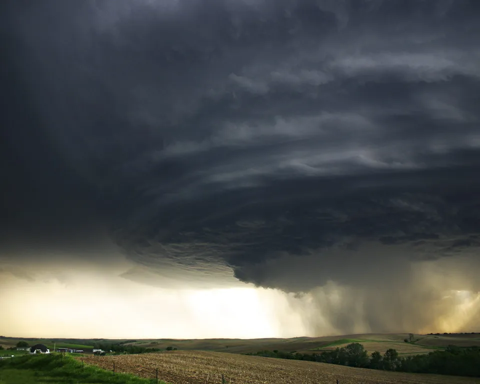 A powerful supercell thunderstorm with dark, swirling clouds and visible rain shafts.