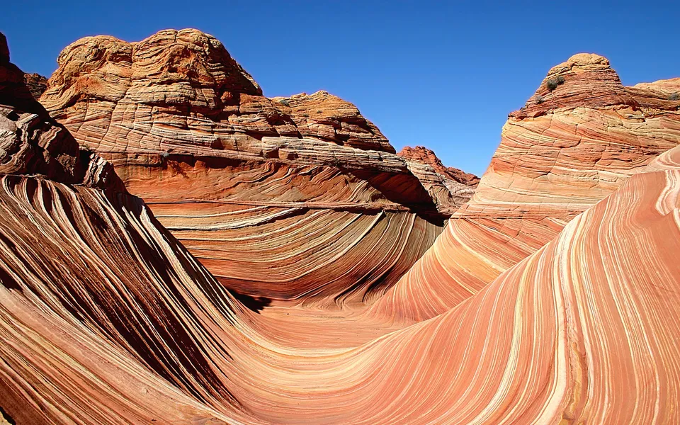 Swirling patterns of red, orange, and white sandstone under a clear blue sky.