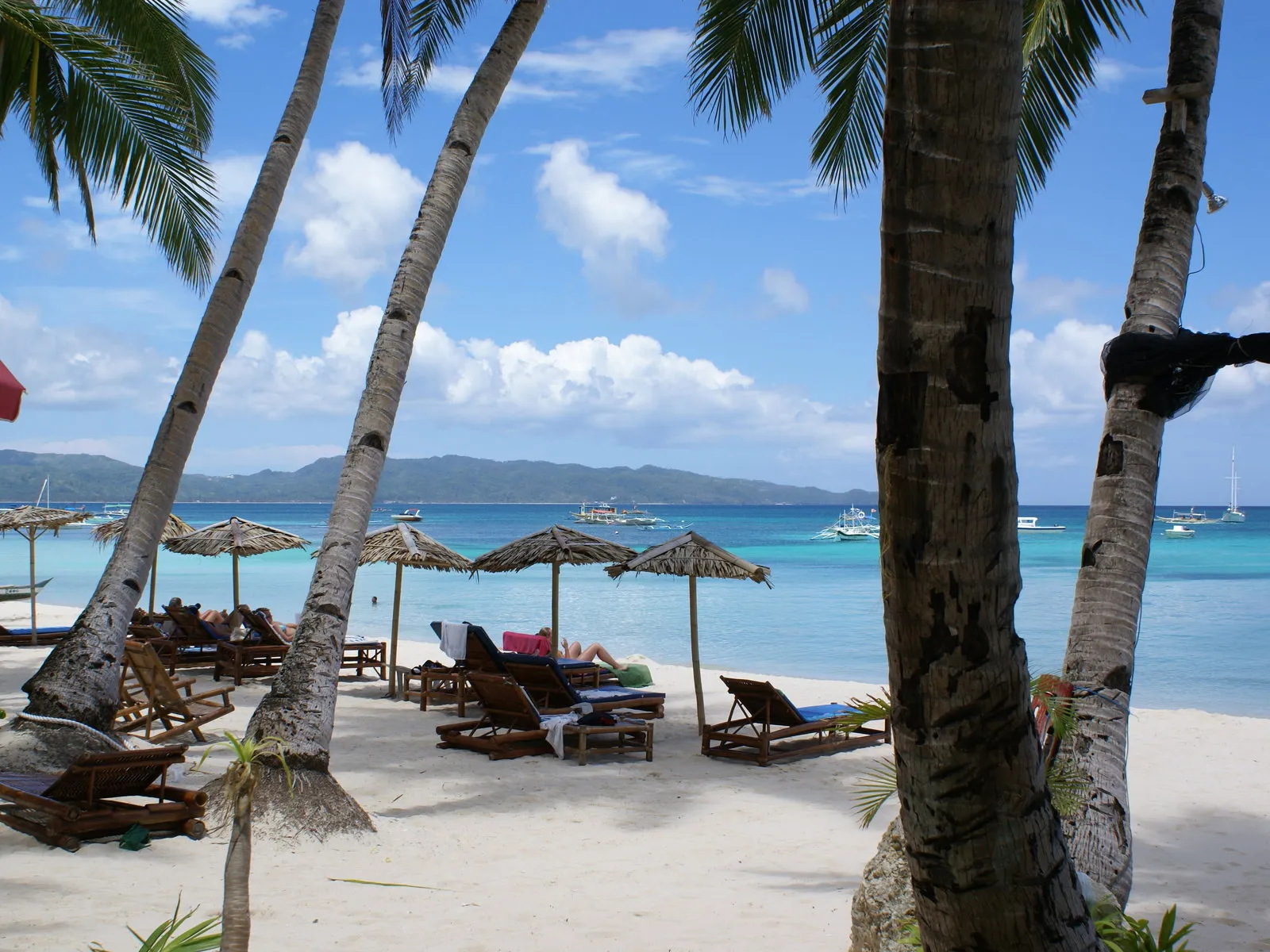 Tropical beach scene with lounge chairs and thatched umbrellas.