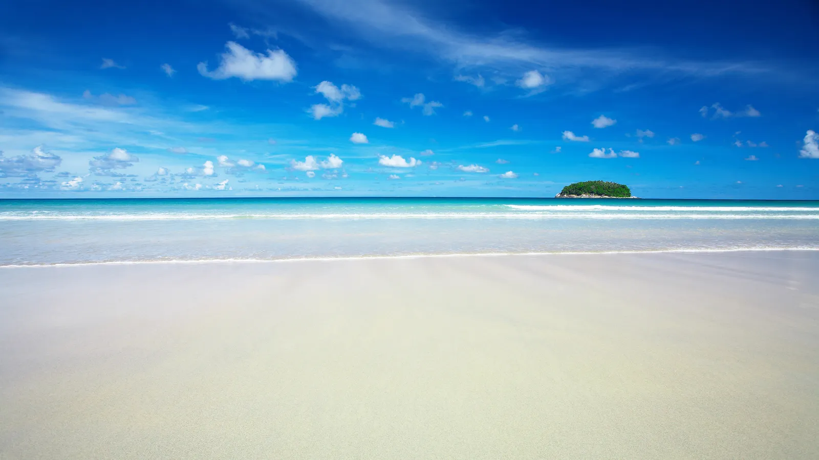 A wide, sandy beach meets the turquoise ocean under a bright blue sky with scattered white clouds. A small, green island is visible on the horizon.
